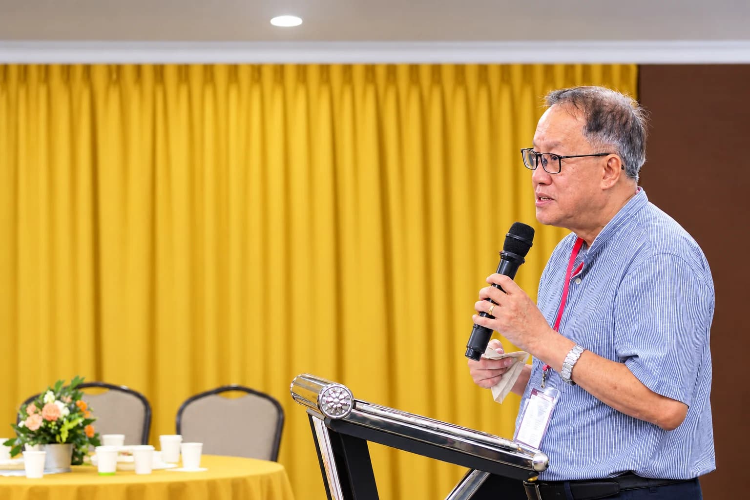 A member speaking into a microphone at the lectern during a fellowship gathering